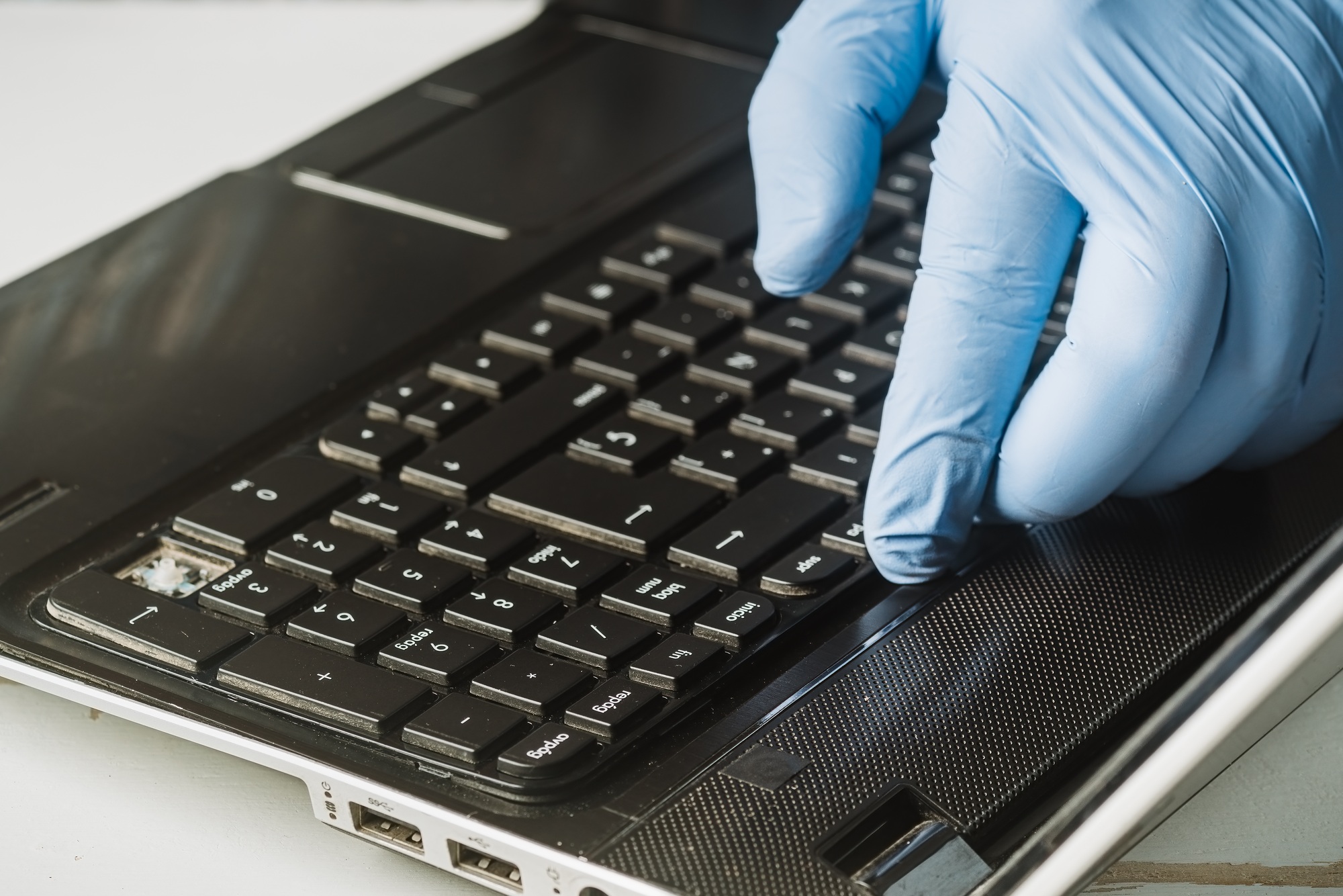 Close-up of a hand removing a dirty keyboard from a laptop PC